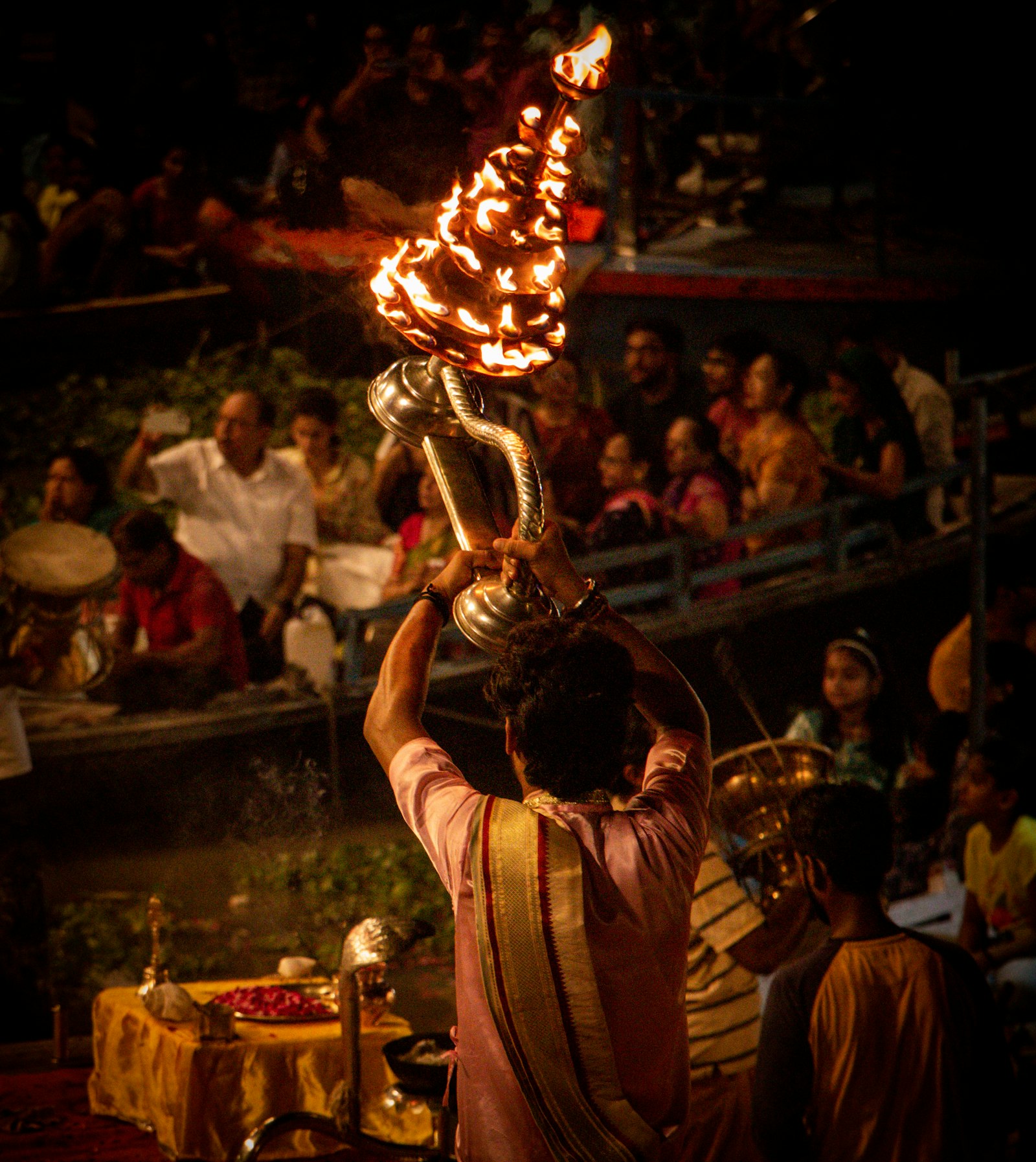 A priest raises a tiered flame lamp at the evening Ganga aarti