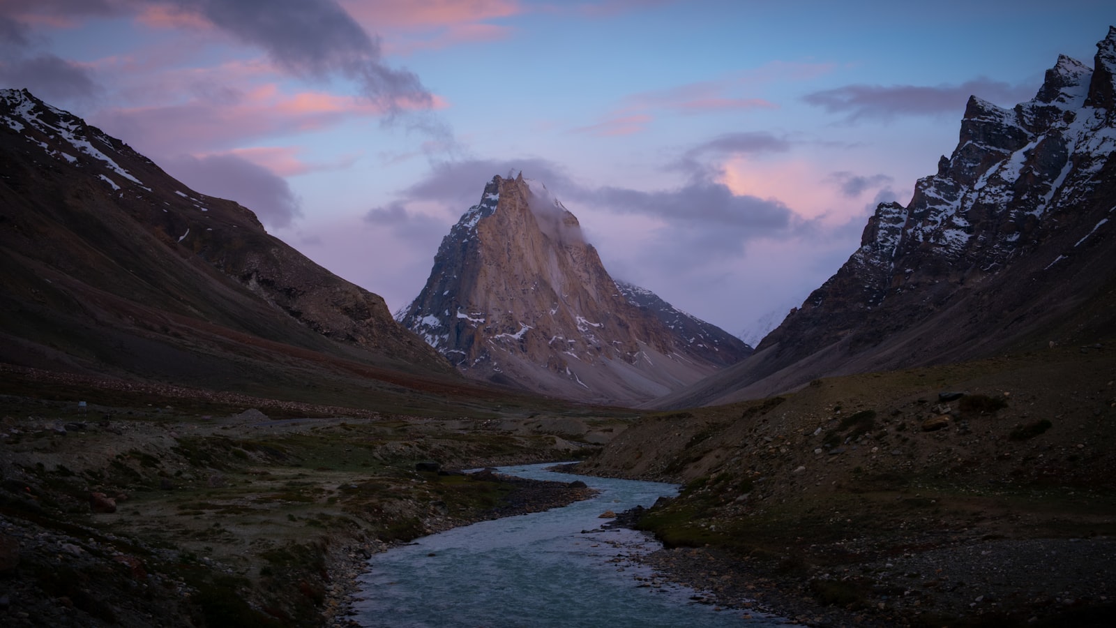 A glacial river winding through a high Himalayan valley at dawn