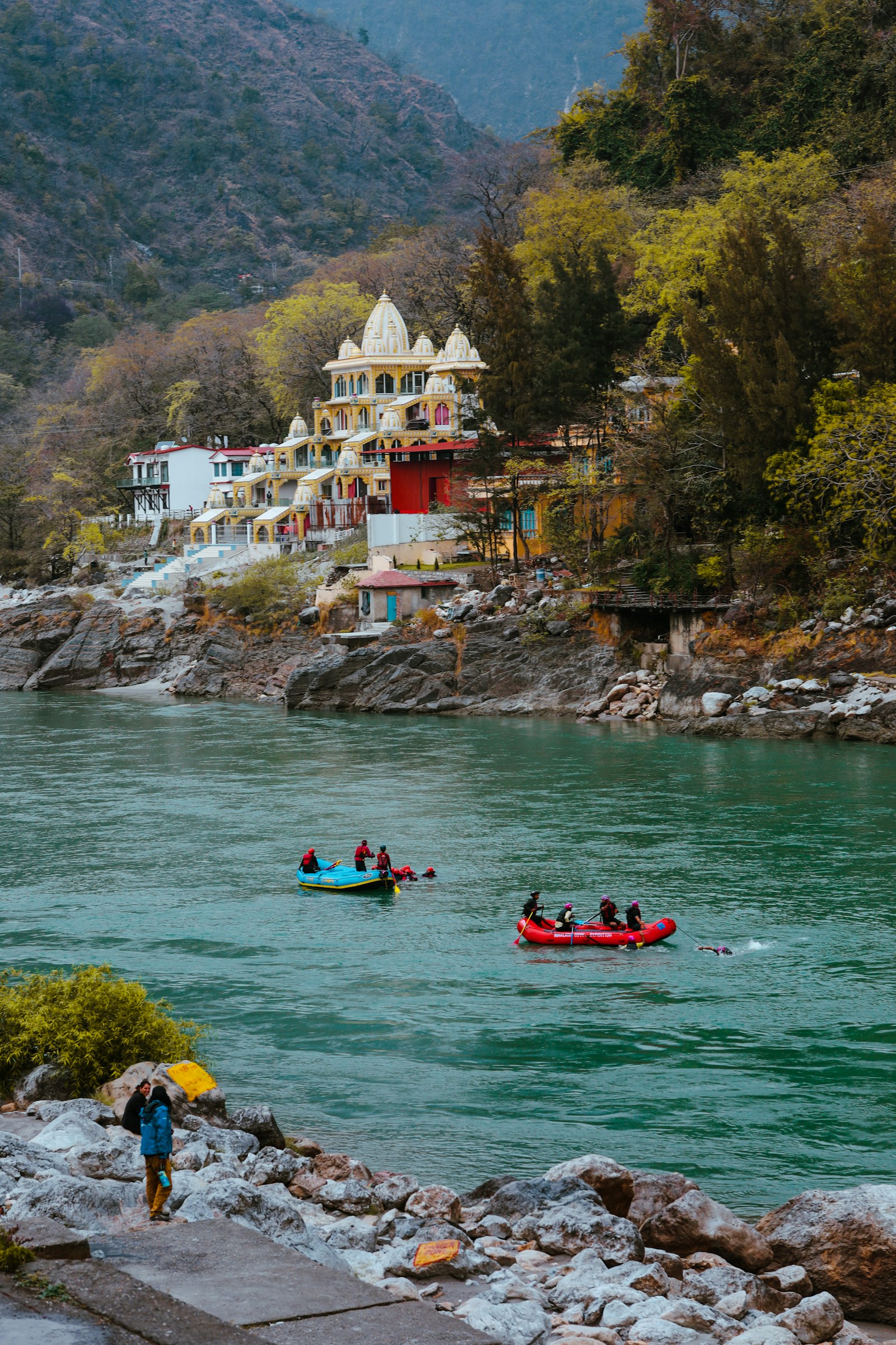 Rafts on the turquoise Ganga below a riverside temple