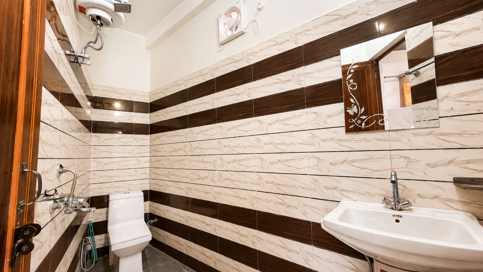 Clean attached bathroom with tiled walls, toilet, shower, and sink